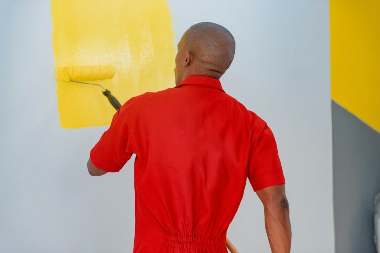 Painter rolling yellow paint on a wall